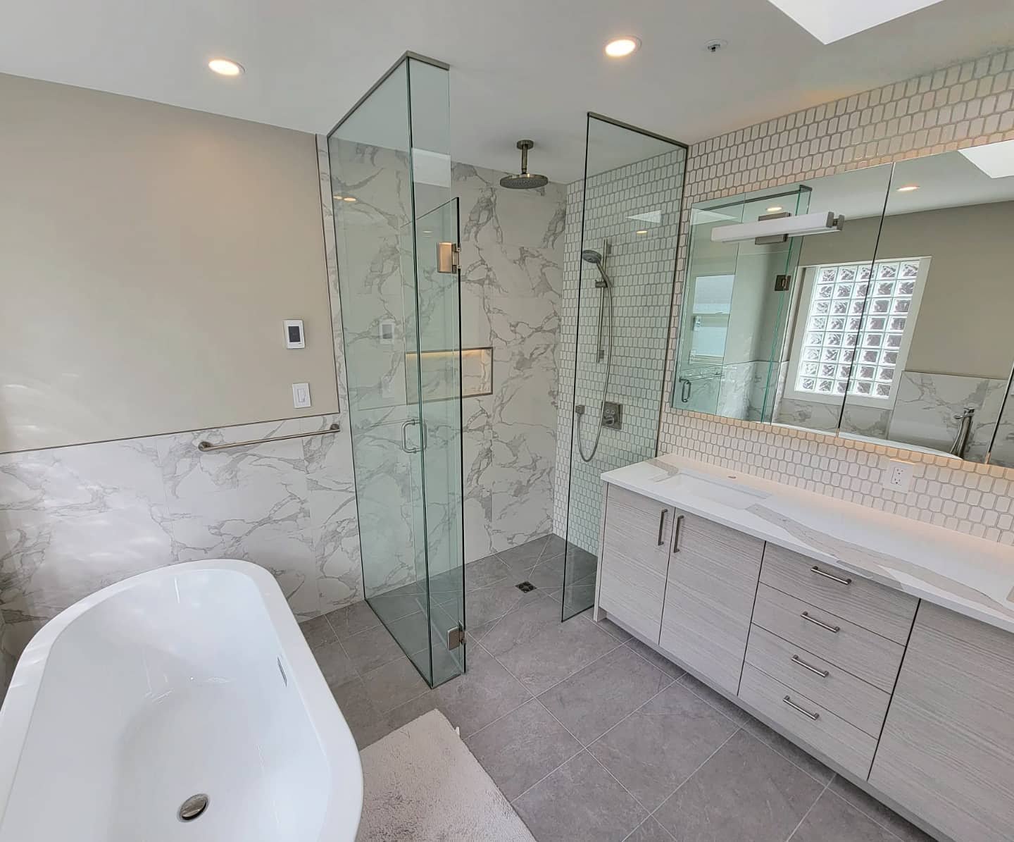 Bathroom with a freestanding tub, glass shower and white vanity