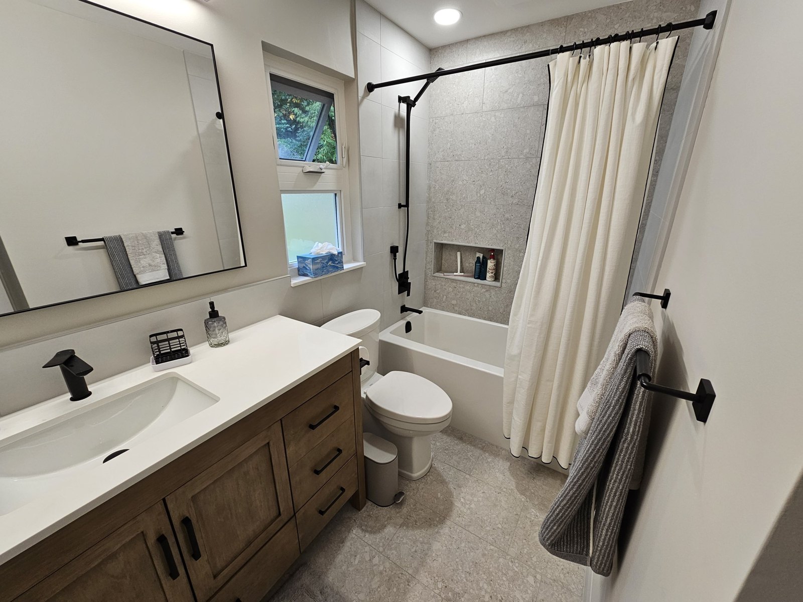 Bathroom with wood vanity, tub and black shower fixtures