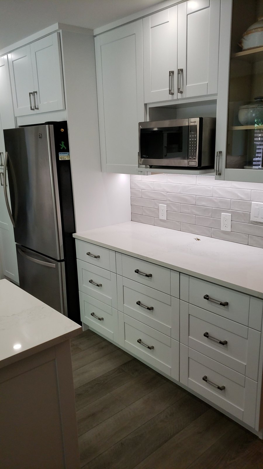 White kitchen cabinetry with built-in microwave and tiled backsplash